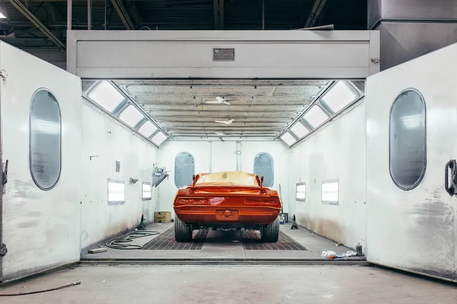 Freshly painted red car inside an automotive paint booth