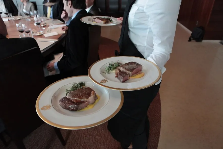 Server carrying plated meals in a restaurant