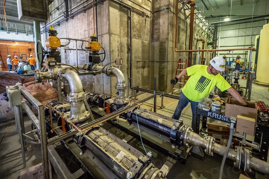 Worker in a hard hat inspecting equipment on a factory floor
